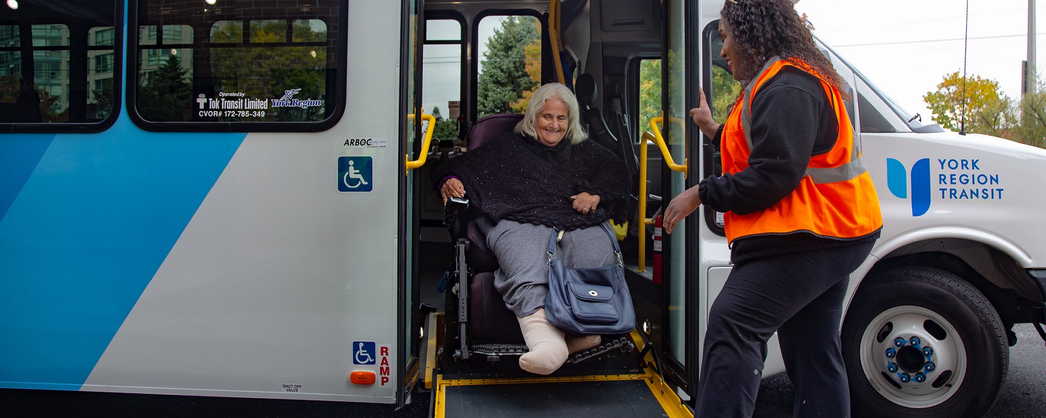 YRT staff helping women in wheelchair on ramp from bus