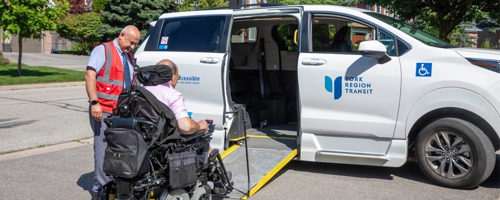 transit operator helping a man in a wheelchair board a paratransit vehicle