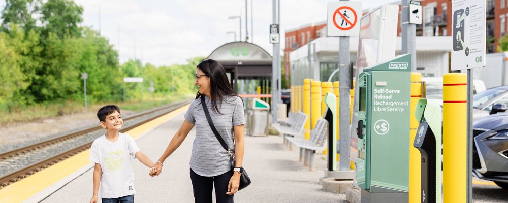 a young child and a women walking along a GO Train platform